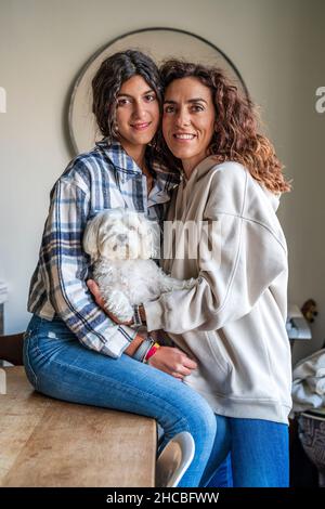 Felice madre con figlia seduta con cane a tavola Foto Stock