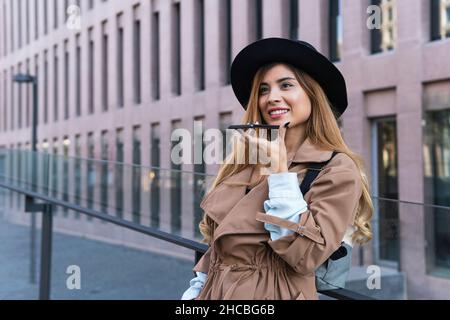 Donna che invia messaggi vocali tramite telefono cellulare in città Foto Stock