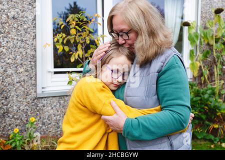 Nonna sorridente che abbraccia la nipote nel cortile Foto Stock