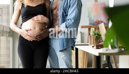 Uomo felice di toccare la pancia di sorridente donna incinta a casa Foto Stock