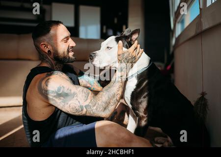 Uomo sorridente seduto con il cane a casa Foto Stock