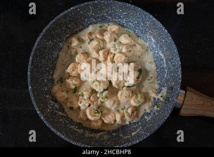 Gamberi all'aglio al burro cotti in una padella e presentati su un piano in marmo nero lucido. Gamberi cotti al burro e salsa all'aglio. Foto Stock