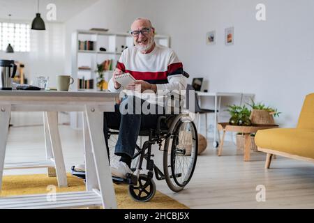 Uomo d'affari premuroso con appunti su sedia a rotelle a casa Foto Stock