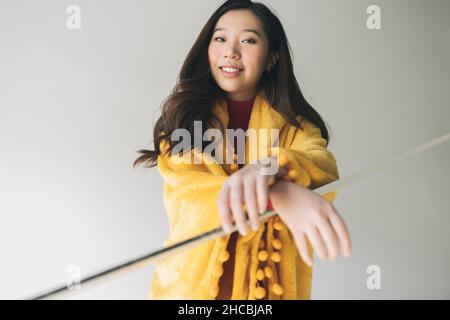 Sorridente giovane donna che tiene la tazza di caffè sui gradini in casa Foto Stock