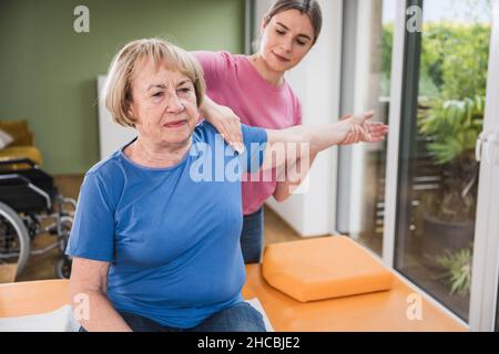 Fisioterapista massaggiante mano della donna disabile sul tavolo Foto Stock