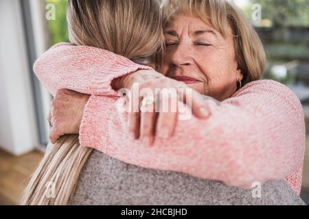 Sorridente anziana che abbraccia l'operatore sanitario a casa Foto Stock