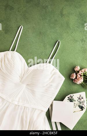 Scatto dello studio della scheda di invito, nastro, anello di aggancio e coppia degli anelli di cerimonia nuziale appiattito su sfondo rosa Foto Stock