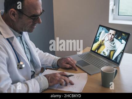 Medico che discute rapporti medici con il paziente in videochiamata attraverso il portatile in clinica Foto Stock