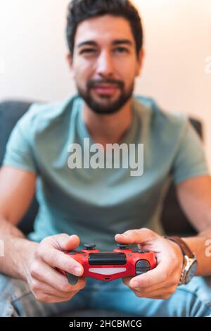 Un uomo allegro con joystick che gioca il videogioco a casa Foto Stock