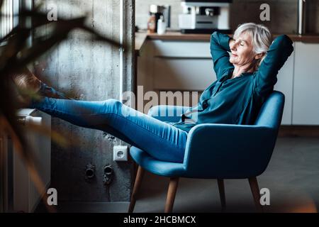 Donna d'affari sorridente con le braccia incrociate utilizzando cuffie per realtà virtuale in ufficio Foto Stock