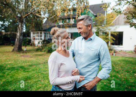 Donna sorridente che ricopre il volto dell'uomo con la rete da pesca a farfalla sul cortile Foto Stock