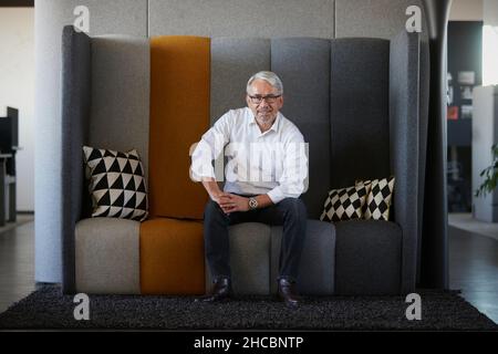 Uomo d'affari maturo seduto sul divano sul posto di lavoro Foto Stock