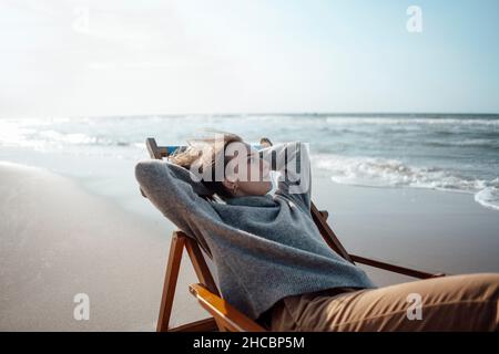 Uomo anziano seduto su sedia da spiaggia Foto Stock