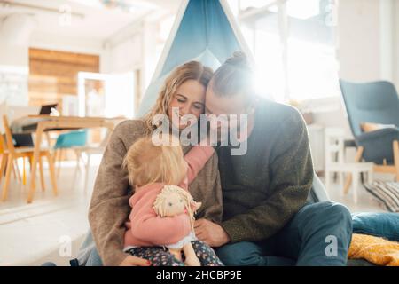 Libro di lettura della figlia con la famiglia a casa Foto Stock