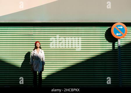Giovane donna di fronte al muro corrugato verde Foto Stock