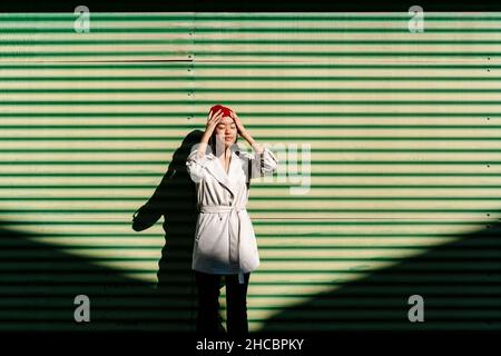Giovane donna con testa nelle mani in giorno di sole Foto Stock