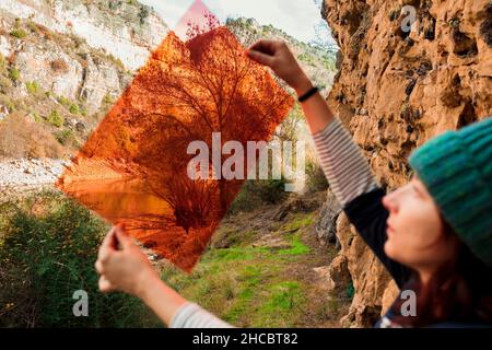 Donna che guarda gli alberi attraverso la plastica rossa Foto Stock