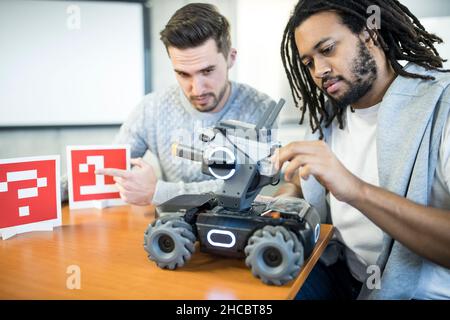 Gli ingegneri analizzano il serbatoio di combattimento robotizzato in officina Foto Stock