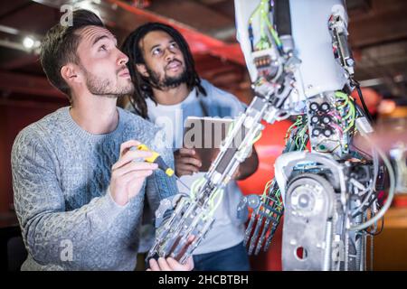 Ingegneri che esaminano il braccio robotico in officina Foto Stock