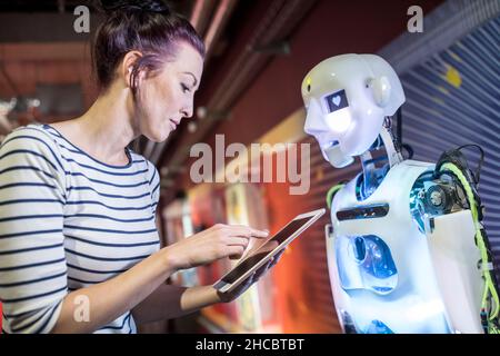 Il tecnico programma il robot umano tramite il tablet PC in officina Foto Stock