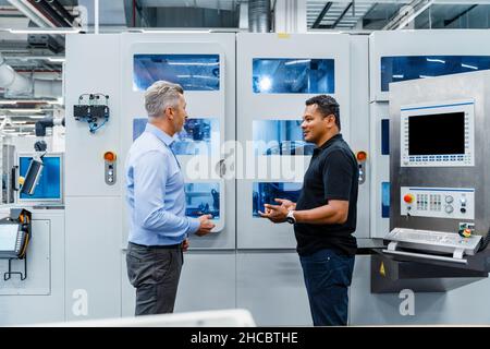 Uomo d'affari che ha discusso con il tecnico di manutenzione nell'industria automatizzata Foto Stock