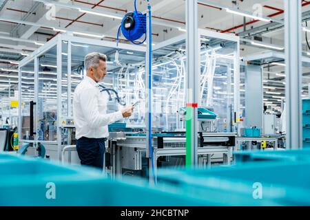Uomo d'affari che utilizza il tablet digitale in fabbrica Foto Stock