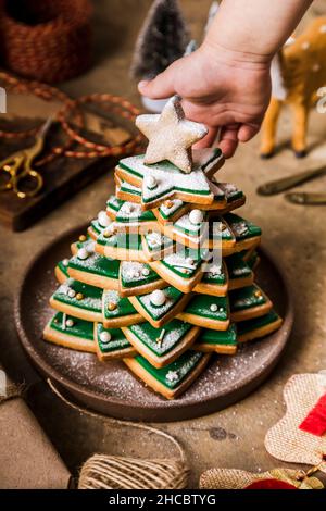 Mano della donna che tiene il pop della torta di Natale sopra il piatto Foto Stock