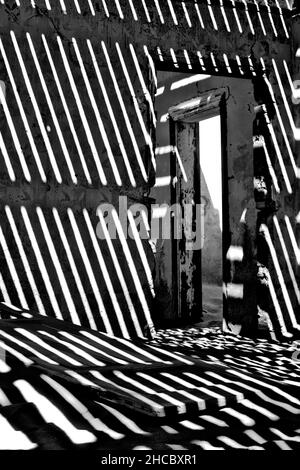 Foto verticale di una casa abbandonata all'interno con ombre nella città fantasma Kolmanskop, Namibia Foto Stock