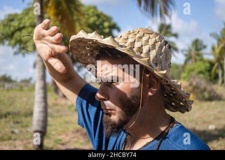 Giovane uomo bianco in un cappello rustico che copre la luce del sole con la mano. Concetto di riscaldamento globale. Foto Stock
