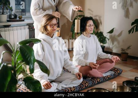 Gruppo o gente guarigione del suono, massaggio di vibrazione e terapia alternativa. Cura della salute mentale, meditazione e relax. Terapista che gioca a diverse età Foto Stock