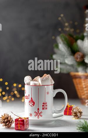 Marshmallows e una tazza di latte sullo sfondo dell'albero di Natale Foto Stock