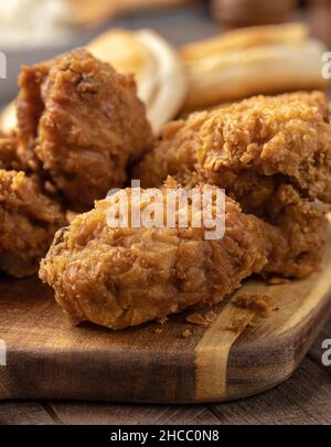 Primo piano di una cena con coscia di pollo fritta croccante su un tagliere Foto Stock
