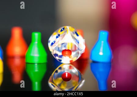 Foto di un dado e di un gettone chiari su una superficie riflettente Foto Stock