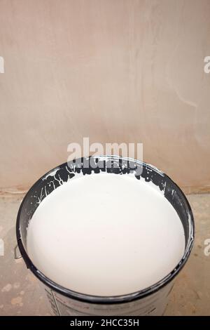 Latta di vernice bianca accanto alla parete intonacata di gesso Foto Stock