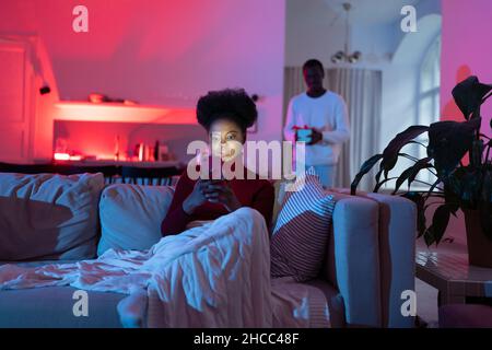 L'uomo nero amorevole saluta la moglie con il compleanno a casa, il marito  che dà la sua scatola regalo e sorridente, seduto insieme sul divano Foto  stock - Alamy