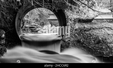 Scala di grigi della diga d'acqua abbandonata e mulino ad acqua Foto Stock