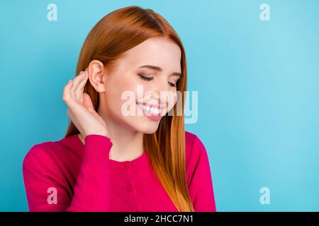 Ritratto di attraente allegro cute sognante ragazza rossa-capelli posa fissaggio capelli isolati su sfondo di colore blu vivo Foto Stock