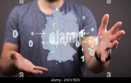 Primo piano delle mani che tengono il modello virtuale della mappa tedesca con numeri binari. Foto Stock