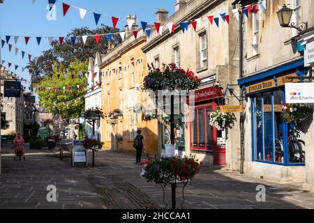 I negozi sono decorati con bunting e cestini di fiori sulla tradizionale High Street di Corsham nel Wiltshire. Foto Stock