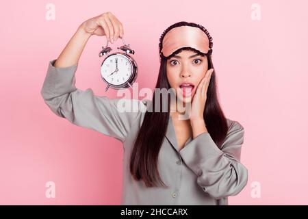 Ritratto di bella trendy stupito stunned ragazza che tiene orologio chiamata awake isolato su rosa pastello sfondo colore Foto Stock