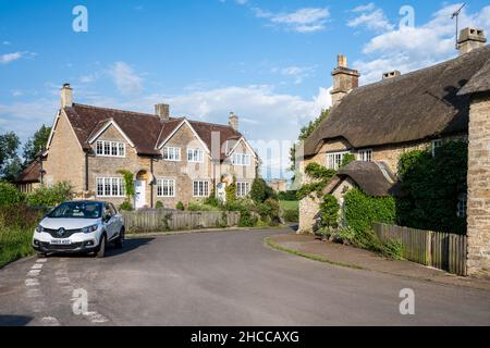 Tradizionali cottage in pietra con piante da arrampicata e recinzioni di picket nel villaggio di campagna di Lullington in Somerset. Foto Stock