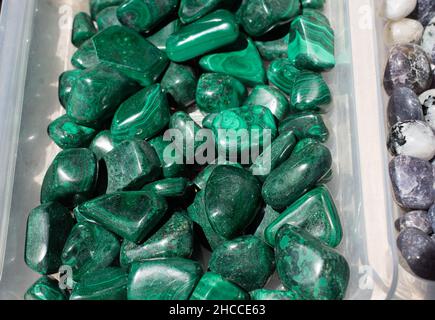 Contenitore di plastica riempito con molte gemme di Malachite verde Foto Stock