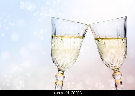 Due bicchieri di cristallo con brindisi con champagne per una festa di nuovo anno, bolle bokeh sfocate sullo sfondo chiaro, spazio copia, fuoco selezionato, profondità stretta o Foto Stock