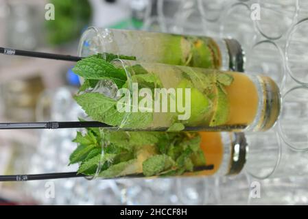 Shot verticale di tre bicchieri di cocktail freschi con menta e lime con una paglia Foto Stock
