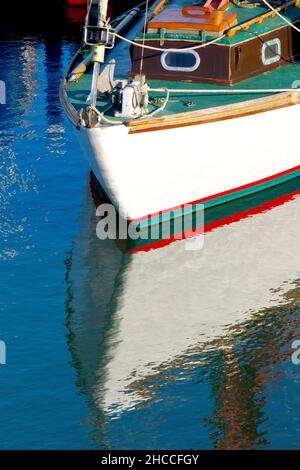 L'arco di un piccolo yacht e il suo riflesso nelle acque relativamente calme del porto di Arbroath, Angus, Scozia, Regno Unito. Foto Stock