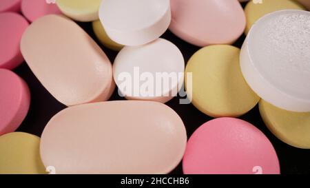 Tablet su un giradischi. Pillole multicolore giacciono sul tavolo. Le compresse sono sparse sul tavolo medico rotante. Laboratorio di analisi. L'inve Foto Stock