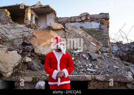 Un uomo vestito come Babbo Natale si trova vicino alle macerie nella città vecchia di Mosul.un'iniziativa lanciata da volontari iracheni della Mosul Eye Foundation per piantare migliaia di alberi nella città devastata dalla guerra di Mosul, con l'obiettivo di rendere verde Mosul e combattere la desertificazione, Hanno distribuito 100 alberi diversi alle case della città vecchia di Mosul come parte di un progetto volto a piantare 5.000 alberi in tutta la città settentrionale di Mosul, che ancora soffre per la distruzione e la devastazione lasciate dalla guerra contro l'Isis. Foto Stock