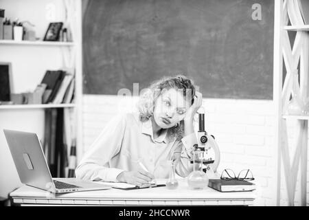 Lavoro stressante dell'insegnante. Pressione nervosa tesa. Ragazza stanca espressione stressante con laptop e microscopio di lavoro di ricerca biologia e. Foto Stock