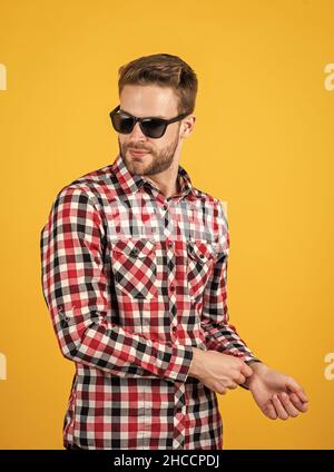 giovane bell'uomo in camicia a scacchi e occhiali da sole ha setole sul viso, stile casual Foto Stock