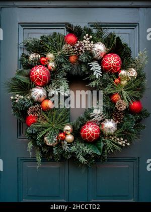 Corona di Natale appesa su una porta d'ingresso Foto Stock